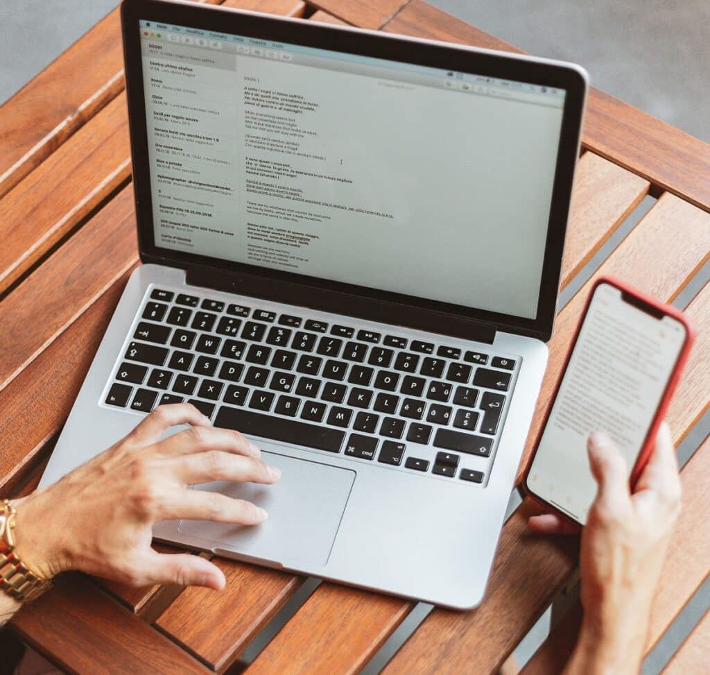person using laptop and phone to check their promotional emails