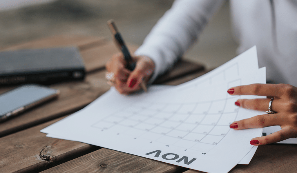 person filling out their marketing calendar